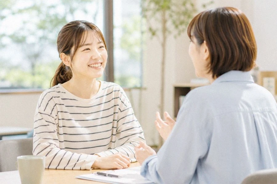 カフェでノートPCを囲んで話す学生と社員