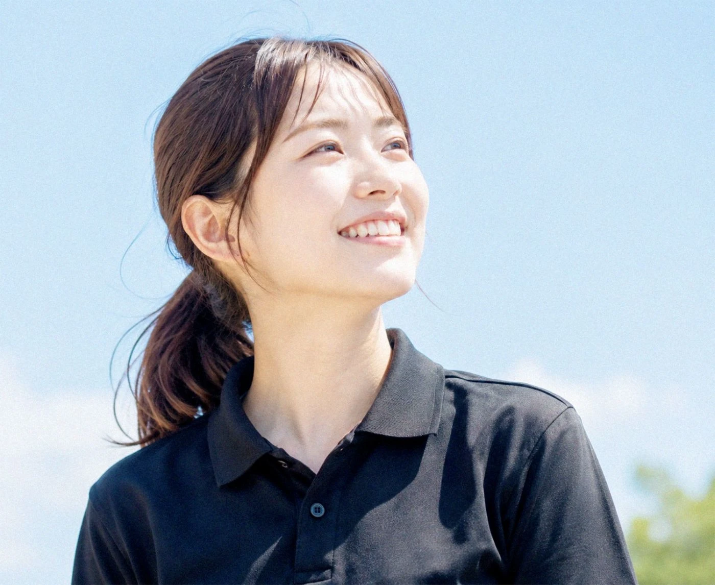 タブレットを抱えて空を見上げる学生